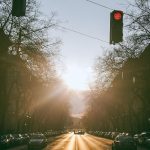 Via asfaltada com veículos entre edifícios sob forte luz do sol