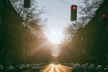 Via asfaltada com veículos entre edifícios sob forte luz do sol