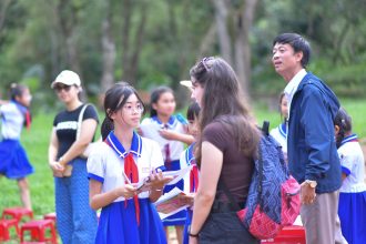 Grupo de estudantes uniformizados participa de uma atividade educativa ao ar livre com professores.