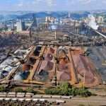 Vista ampla de uma instalação industrial de mineração, com máquinas e pilhas de rejeitos.
