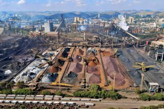 Vista ampla de uma instalação industrial de mineração, com máquinas e pilhas de rejeitos.