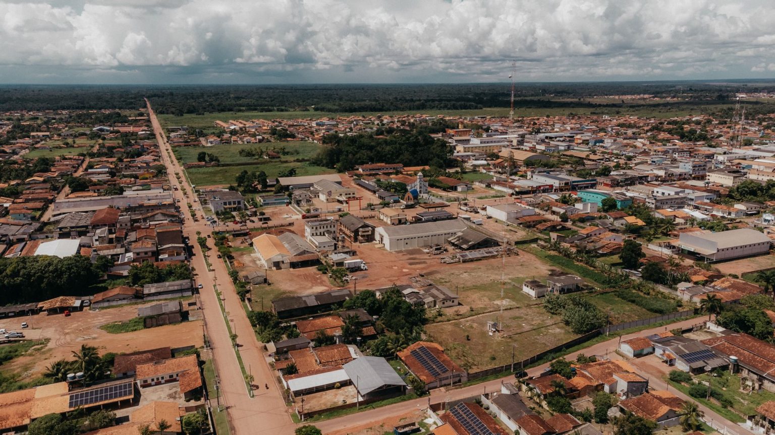 Vista aérea de uma área urbana de Oiapoque, com ruas, casas e vegetação sob céu nublado.