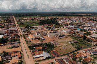 Vista aérea de uma área urbana de Oiapoque, com ruas, casas e vegetação sob céu nublado.