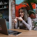Mulher usa Libras durante uma videochamada em um laptop, em ambiente interno.