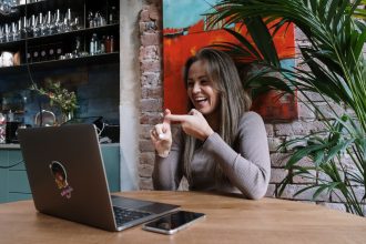 Mulher usa Libras durante uma videochamada em um laptop, em ambiente interno.