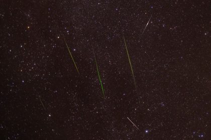 Meteoros traçam riscos luminosos no céu noturno estrelado.
