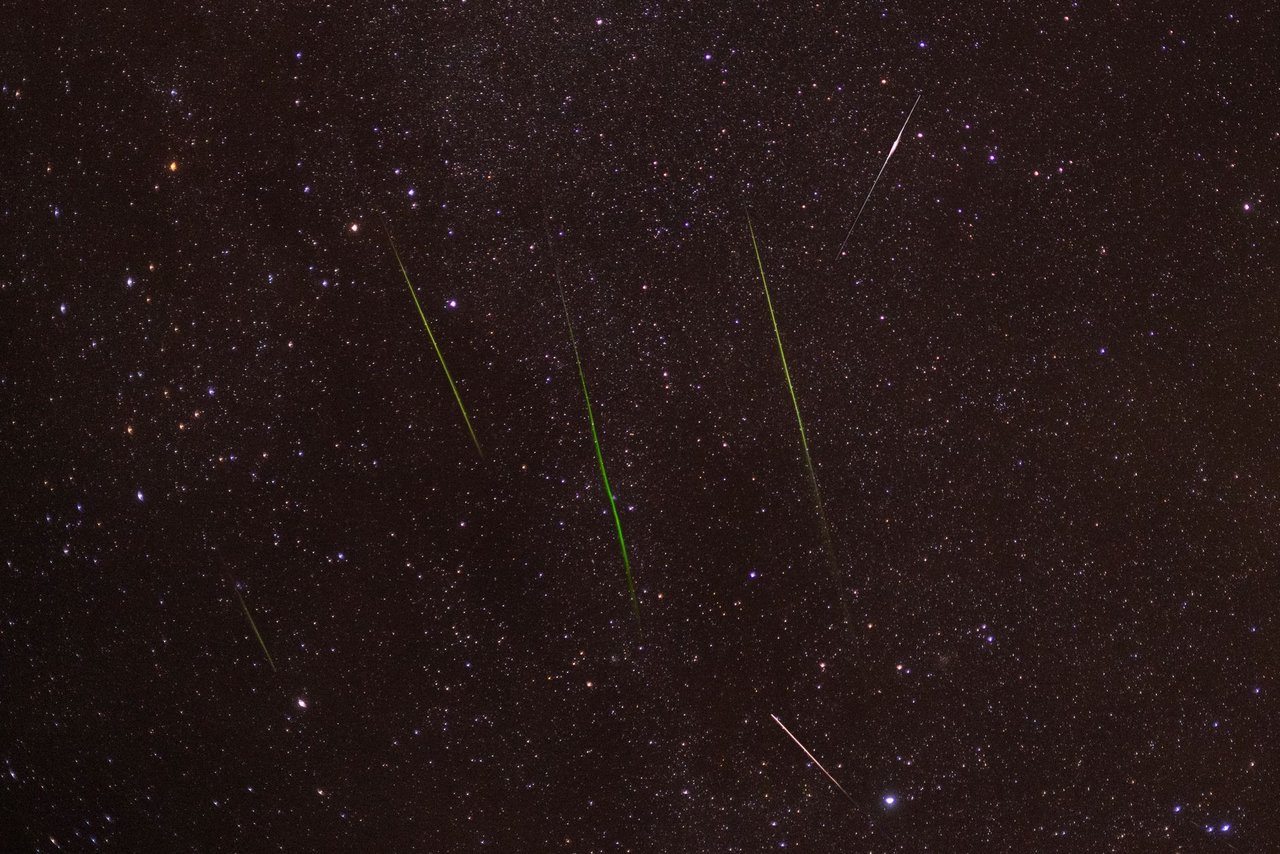 Meteoros traçam riscos luminosos no céu noturno estrelado.