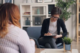 Duas mulheres conversam durante uma sessão de apoio em ambiente reservado.
